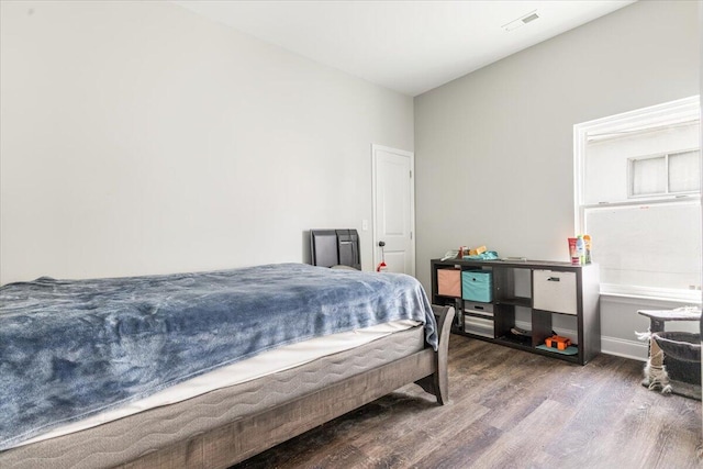 bedroom featuring visible vents, baseboards, and wood finished floors