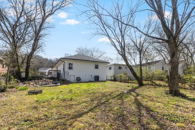 rear view of property with a yard, fence, and central AC