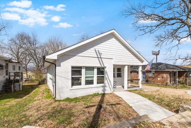 bungalow with brick siding, a porch, and a front lawn