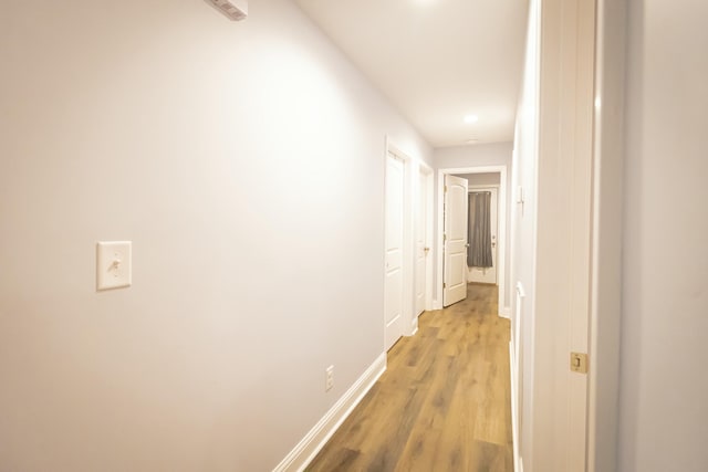 corridor with light wood finished floors and baseboards