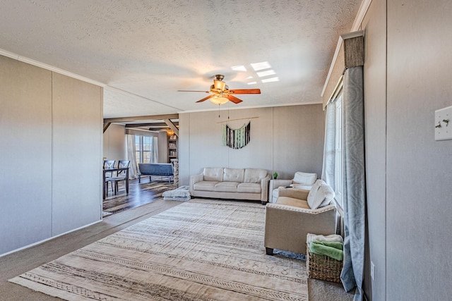 living room with ceiling fan, a textured ceiling, a decorative wall, a skylight, and carpet