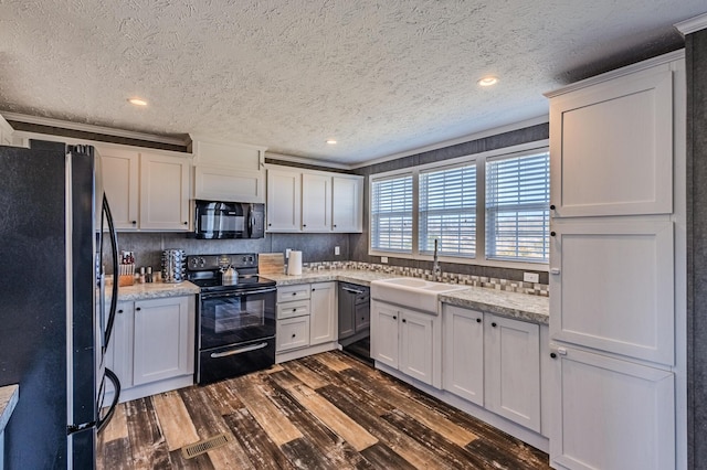 kitchen with dark wood finished floors, white cabinets, a sink, and black appliances