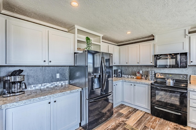 kitchen with tasteful backsplash, light stone countertops, light wood-type flooring, black appliances, and open shelves