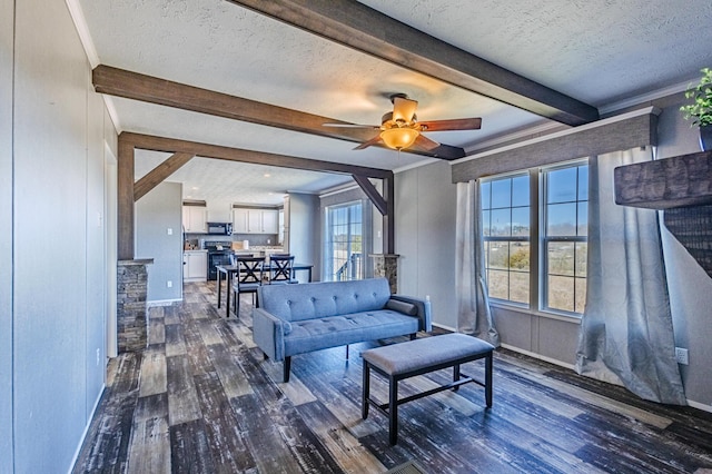 living room with baseboards, dark wood finished floors, a ceiling fan, beamed ceiling, and a textured ceiling