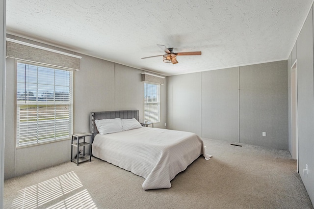 bedroom featuring a ceiling fan, carpet, and a textured ceiling