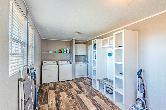 laundry room featuring a textured ceiling, dark wood-type flooring, a sink, independent washer and dryer, and cabinet space