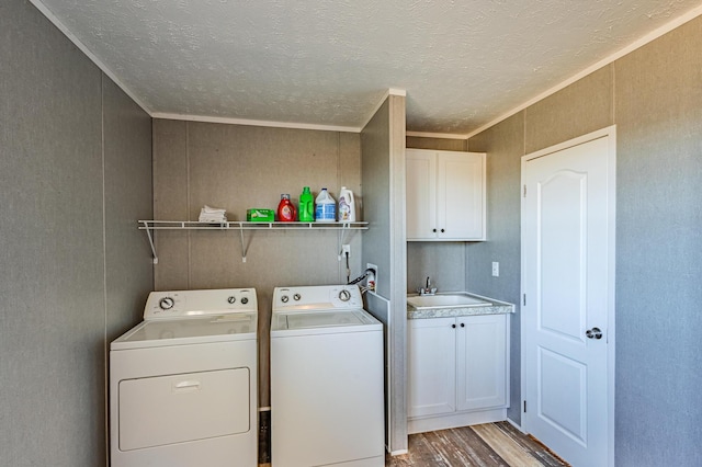 laundry area with crown molding, cabinet space, a sink, separate washer and dryer, and light wood-type flooring