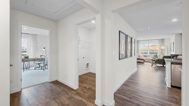 corridor with attic access, visible vents, baseboards, and dark wood-style floors