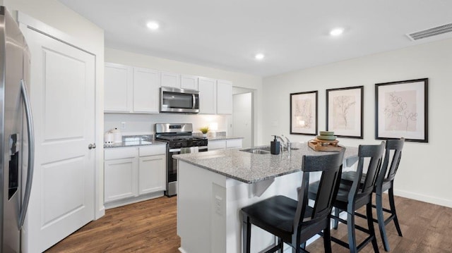 kitchen with stainless steel appliances, a sink, visible vents, white cabinetry, and dark wood finished floors