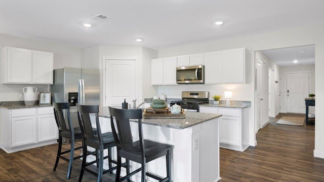 kitchen with visible vents, white cabinets, a breakfast bar, a center island, and stainless steel appliances