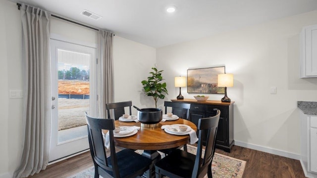 dining room with dark wood-style flooring, visible vents, and baseboards