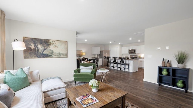 living room featuring baseboards, dark wood-type flooring, and recessed lighting