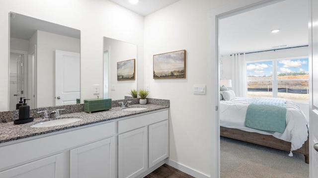 ensuite bathroom featuring double vanity, a sink, baseboards, and ensuite bathroom