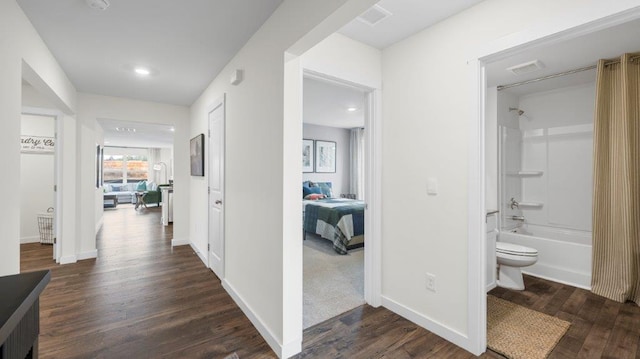 corridor featuring dark wood-style floors, visible vents, and baseboards