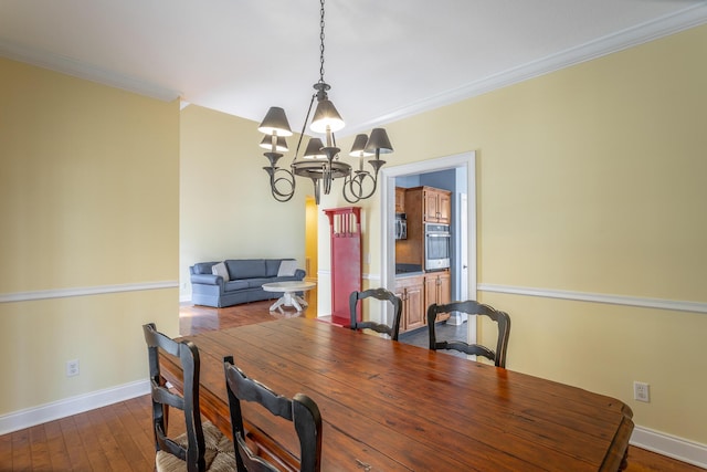 dining space with a chandelier, dark wood-type flooring, crown molding, and baseboards