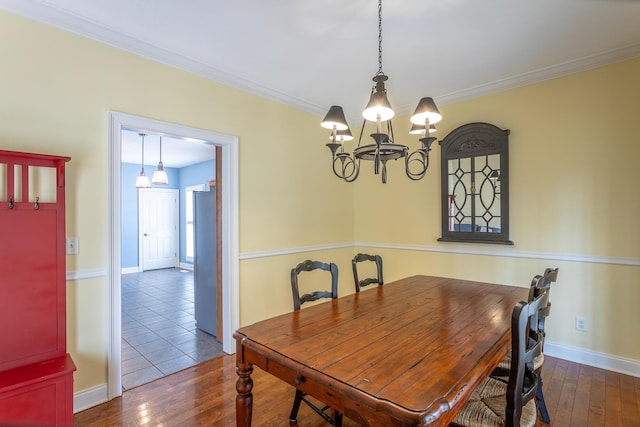 dining room featuring an inviting chandelier, dark wood-style floors, baseboards, and ornamental molding