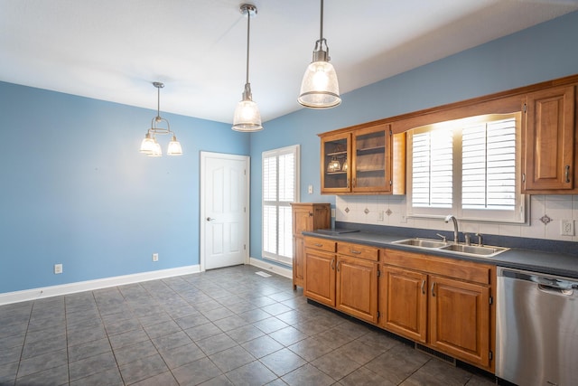 kitchen with a sink, stainless steel dishwasher, dark countertops, and brown cabinetry