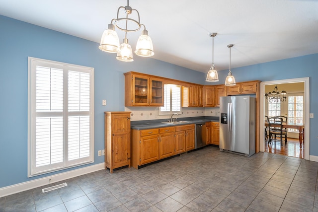 kitchen with dark countertops, visible vents, brown cabinets, appliances with stainless steel finishes, and a sink