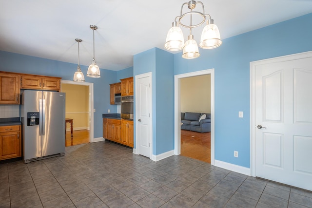 kitchen featuring stainless steel appliances, baseboards, dark countertops, and brown cabinetry