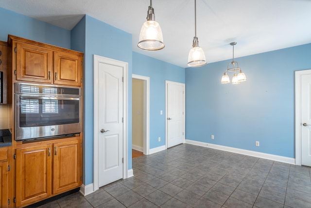 kitchen with oven, decorative light fixtures, baseboards, and brown cabinetry