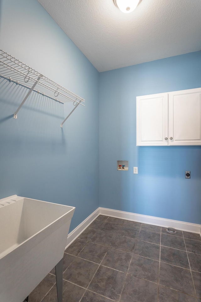 laundry room with a sink, cabinet space, baseboards, and a textured ceiling