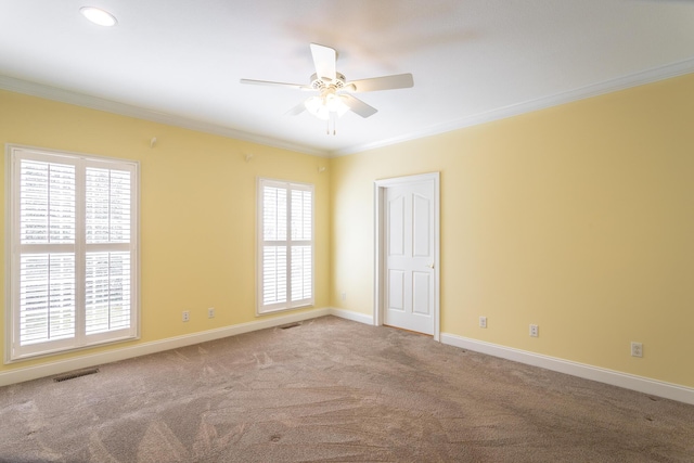 empty room with visible vents, carpet, crown molding, baseboards, and ceiling fan