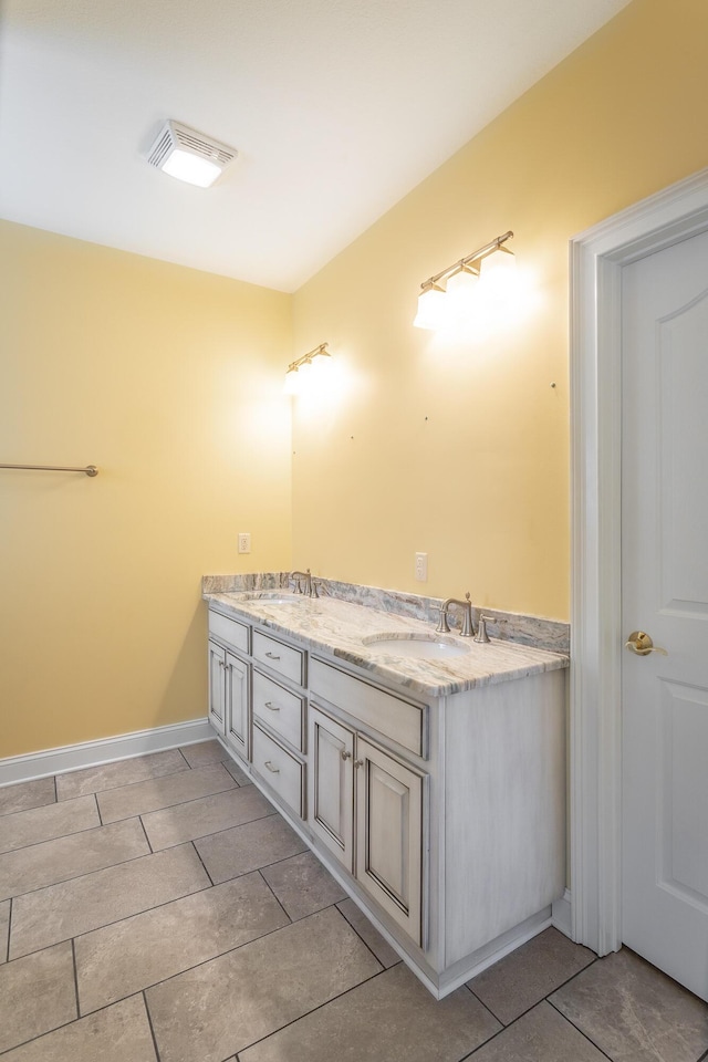 bathroom featuring double vanity, baseboards, visible vents, and a sink