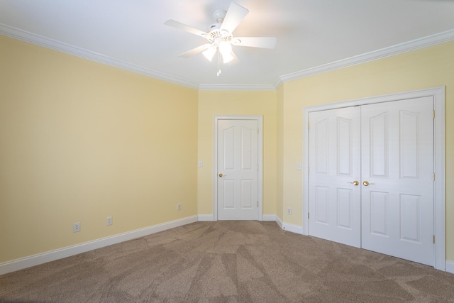 unfurnished bedroom featuring baseboards, carpet floors, ceiling fan, a closet, and crown molding