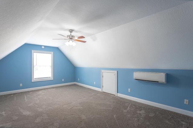 additional living space featuring baseboards, carpet floors, lofted ceiling, an AC wall unit, and a textured ceiling