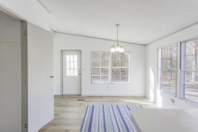 unfurnished dining area with vaulted ceiling, light wood finished floors, and a notable chandelier