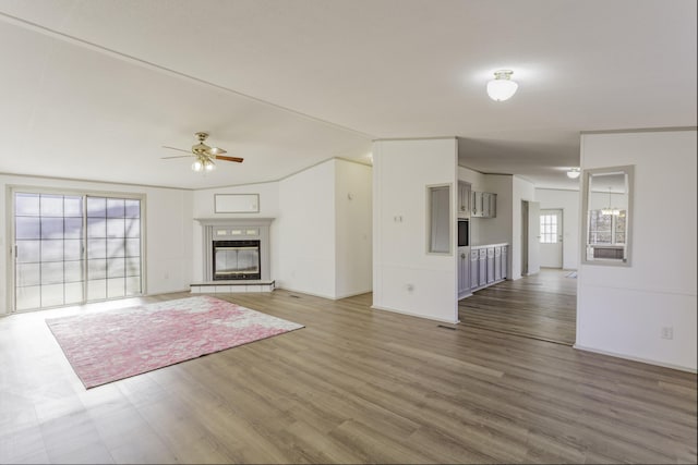 unfurnished living room with lofted ceiling, ceiling fan, a tiled fireplace, and wood finished floors