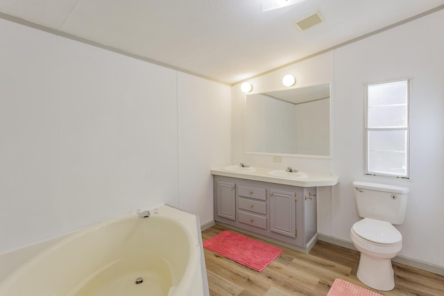 bathroom with toilet, a bathing tub, visible vents, and wood finished floors