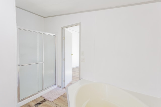 full bathroom featuring a garden tub, a shower stall, visible vents, and wood finished floors