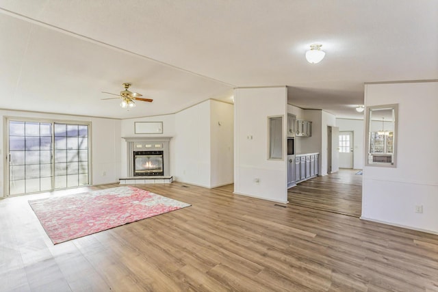 unfurnished living room with a ceiling fan, vaulted ceiling, a fireplace, and light wood finished floors