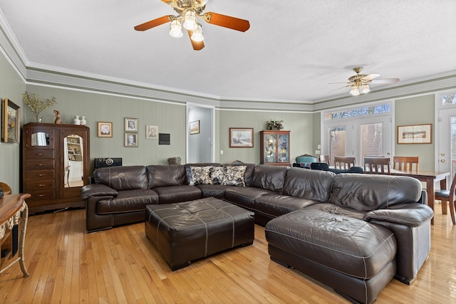 living area with light wood-style floors, ceiling fan, and crown molding