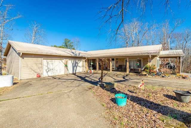 ranch-style house featuring a garage, covered porch, metal roof, and concrete driveway