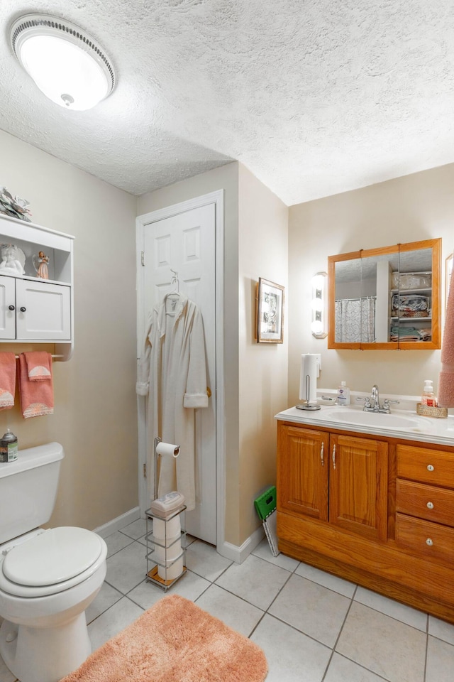 bathroom featuring toilet, vanity, a textured ceiling, and tile patterned floors