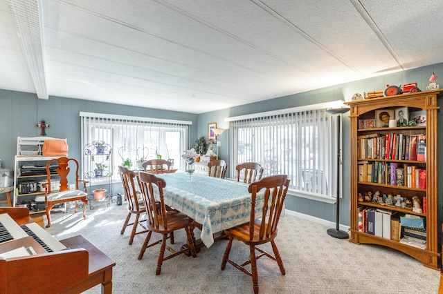 dining space featuring beam ceiling, a textured ceiling, baseboards, and carpet flooring