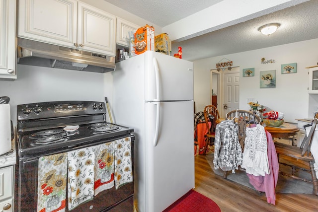 kitchen featuring a textured ceiling, under cabinet range hood, light wood-style floors, black electric range, and freestanding refrigerator