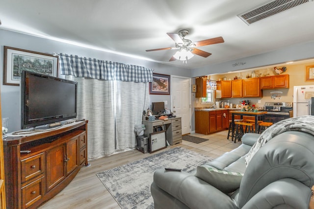 living room with light wood finished floors, ceiling fan, and visible vents