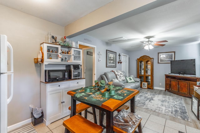 interior space featuring light tile patterned floors, ceiling fan, and baseboards