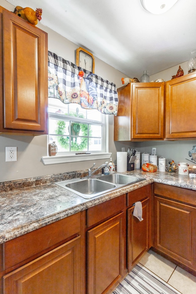 kitchen featuring brown cabinetry, a sink, and light tile patterned flooring