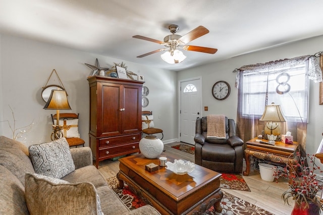 living room with light wood-style floors, baseboards, and a ceiling fan