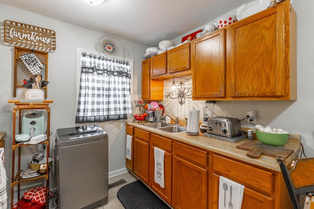 kitchen with a toaster, visible vents, brown cabinets, light countertops, and a sink