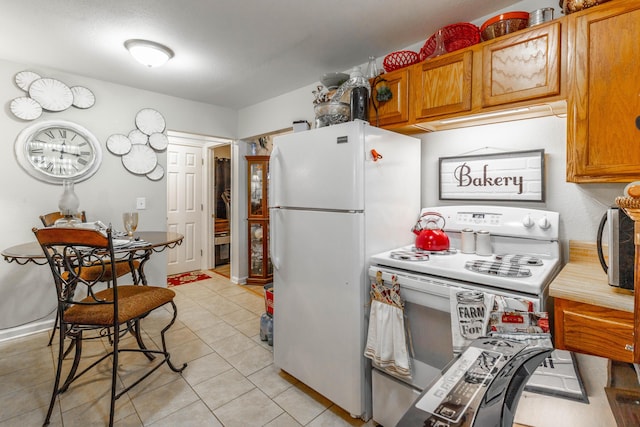 kitchen featuring brown cabinetry, light countertops, white appliances, and light tile patterned flooring