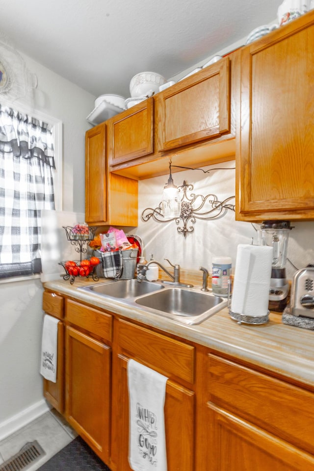 kitchen featuring brown cabinets, light countertops, a sink, and visible vents