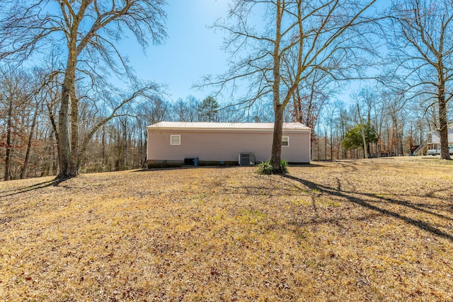 view of property exterior featuring metal roof, central AC unit, and a lawn