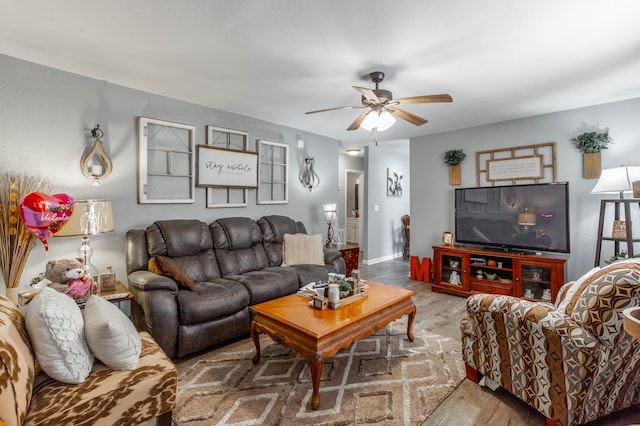 living room featuring ceiling fan, wood finished floors, and baseboards