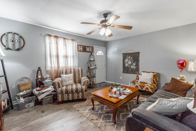 living area with baseboards, a ceiling fan, and wood finished floors