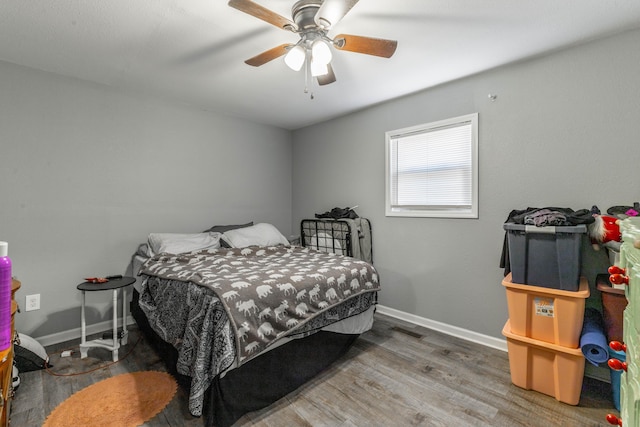 bedroom with a ceiling fan, baseboards, and wood finished floors